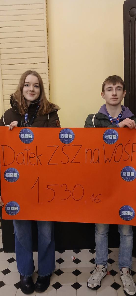 Dwoje uczniów z plakatem przedstawiającym wysokość datków na Wośp od ZSZ Rawicz